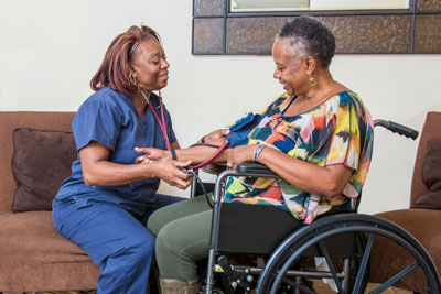 Woman in wheelchair and nurse taking her blood pressure.