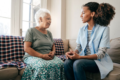 Nurse and patient sitting on a couch talking.